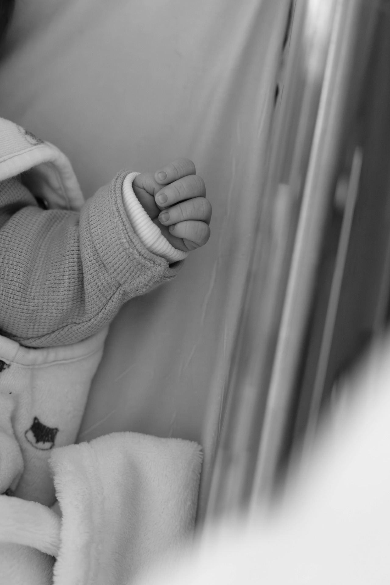 Main d’un bébé venant de naitre, dans son berceau à la maternité, photo en noir et blanc