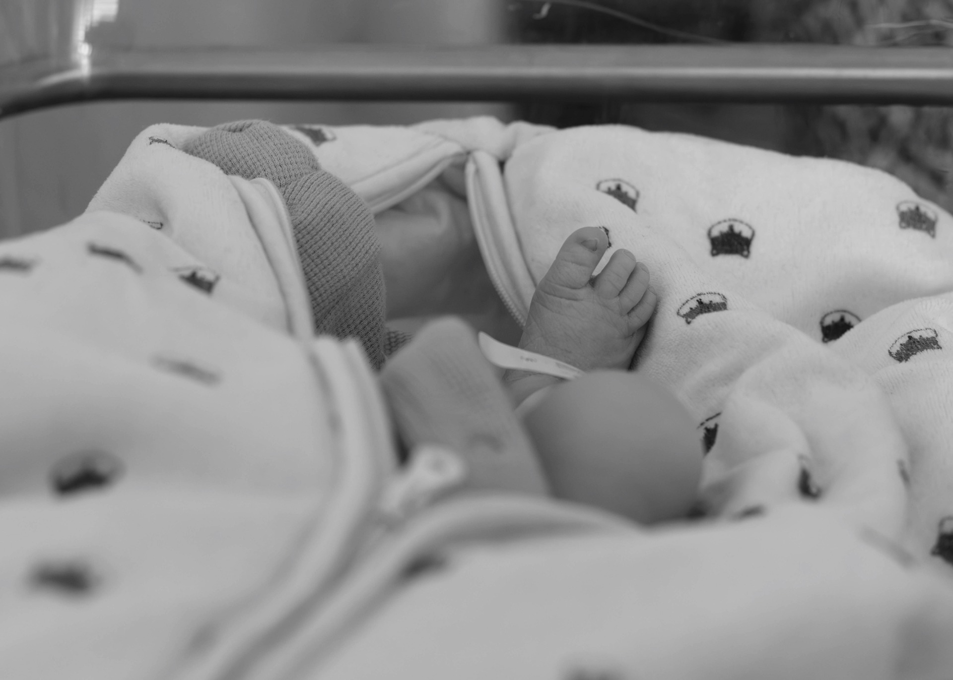 Pied de bébé venant de naitre. Dans son berceau à la maternité. Photo en noir et blanc.