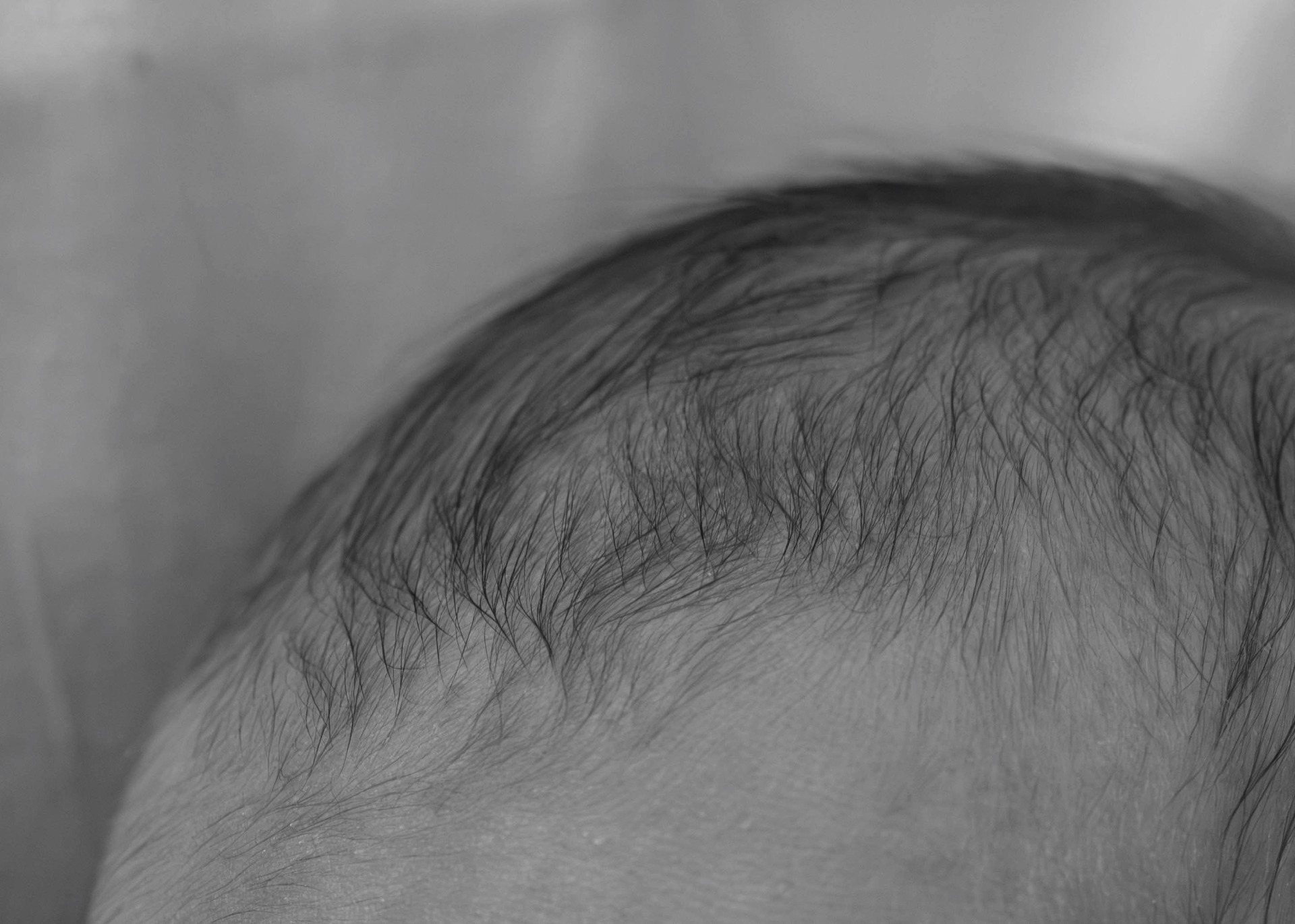 Petit cheveux d'un bébé venant de naitre. Dans son berceau à la maternité. Photo en noir et blanc.